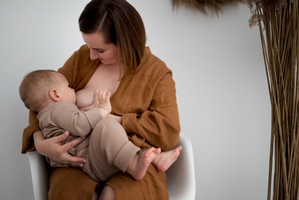 Mulher amamentando seu bebê, destacando a importância do aleitamento materno para a saúde e o desenvolvimento infantil.