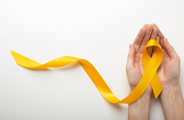 mãos segurando uma fita amarela, simbolizando a campanha Setembro Amarelo, que visa a prevenção do suicídio e a conscientização sobre a saúde mental.