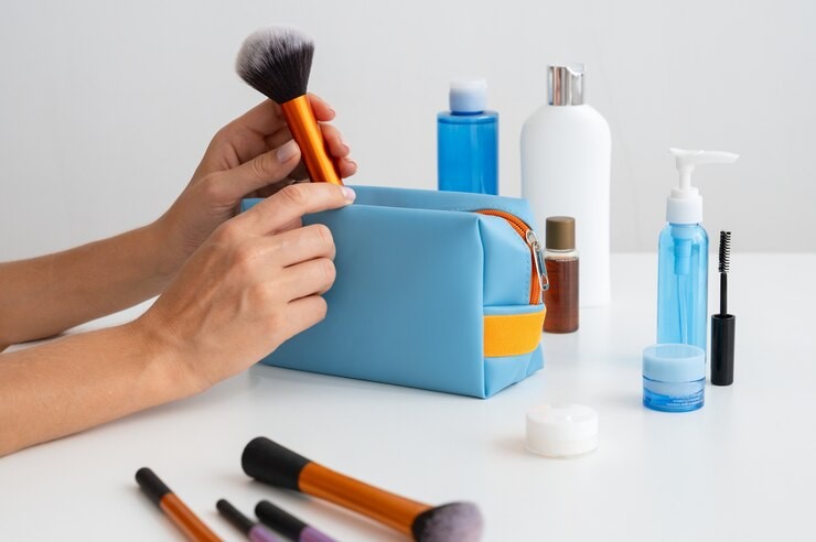 Produtos característicos de kits de cosméticos dispostos sobre um mesa enquanto uma mão feminina os organiza.